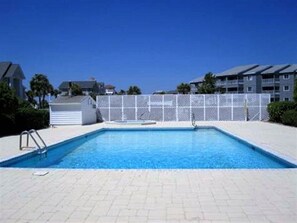 Une piscine rectangulaire avec une clôture blanche en arrière-plan.