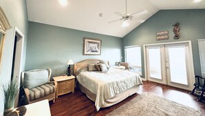 A bedroom with a bed, a nightstand, a lamp, a wicker chair, a window, and a ceiling fan. - 3BR/3BA - Beach, pool, lagoon front and MORE!  (Gulf Shores)