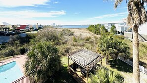 A view of a beachside property with a pool, palm trees, and a wooden gazebo. - 3BR/3BA - Beach, pool, lagoon front and MORE!  (Gulf Shores)