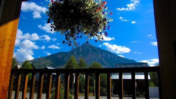 A view of a mountain through a window with a wooden railing.