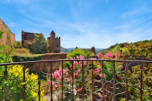 Perched atop a lush landscape, this historic castle features a striking tower amidst vibrant flowers.