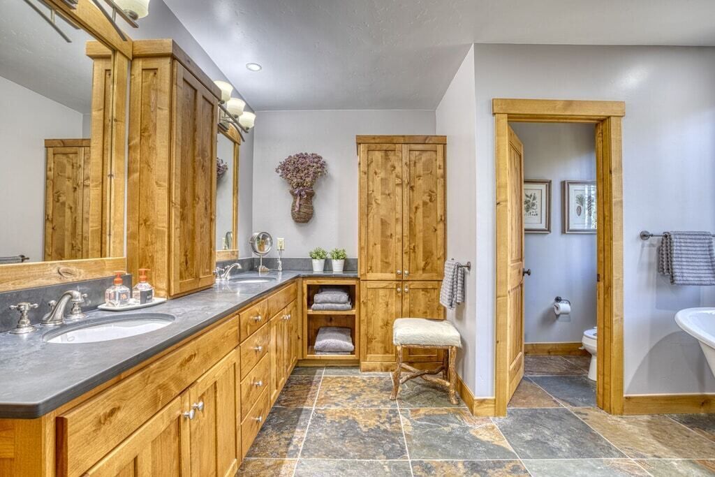A bathroom with wooden cabinets, a large mirror, a sink, and a toilet.