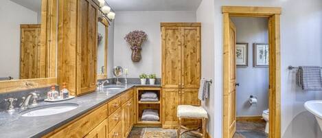 A bathroom with wooden cabinets, a large mirror, a sink, and a toilet.