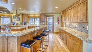Una cocina amplia con armarios de madera, encimeras de granito y una isla grande con taburetes de bar.
