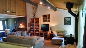 A cozy living room with a sectional sofa, a TV, a bookshelf, and a fireplace.