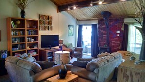 A cozy living room with a fireplace, a television, and a bookshelf filled with books and games.