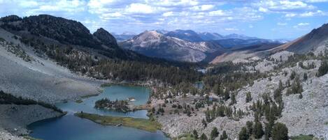 A mountainous landscape with a lake surrounded by rocky terrain and sparse vegetation.