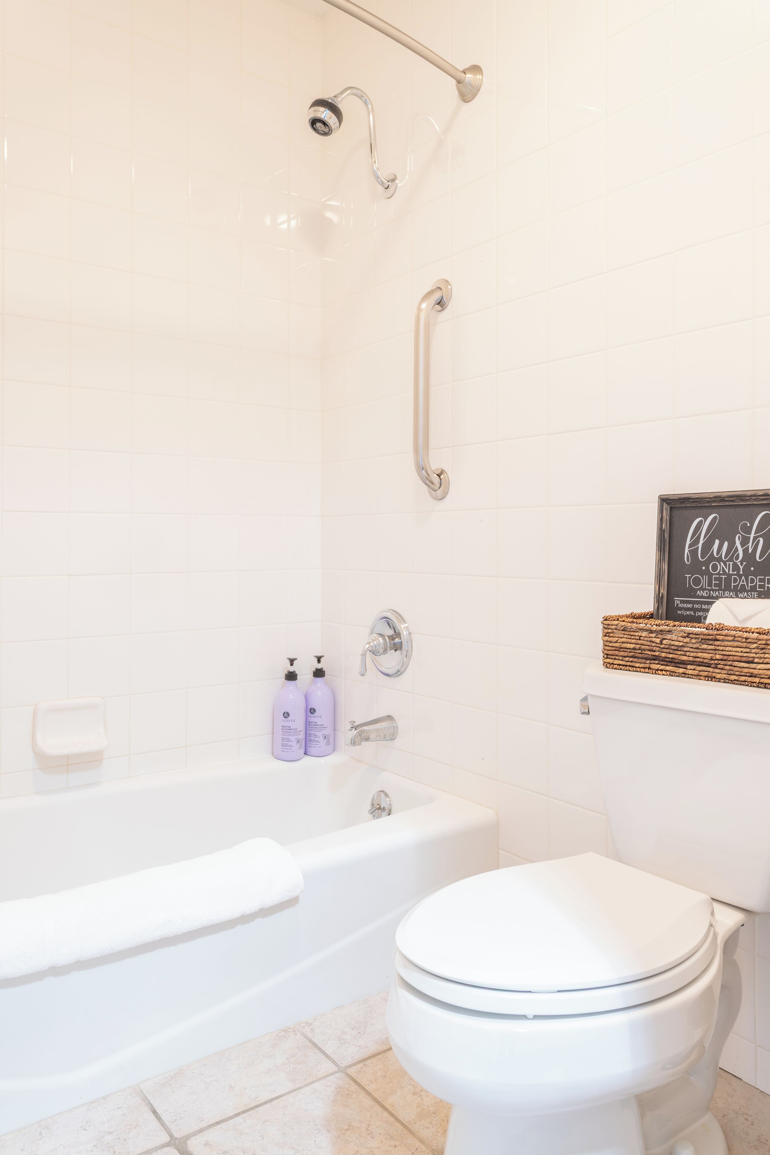 A bathroom with a white bathtub, toilet, and a shower area.