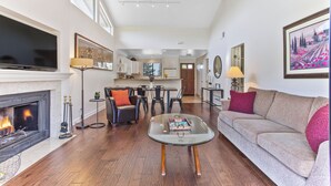 Un salón amplio con chimenea, un sofá, una mesa de centro y un televisor.