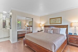 Une chambre à coucher avec un grand lit, une table de chevet avec une lampe, une commode et un miroir.
