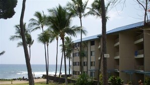 Ein Hotel direkt am Strand mit mehreren Etagen, Palmen und Blick auf den Ozean.