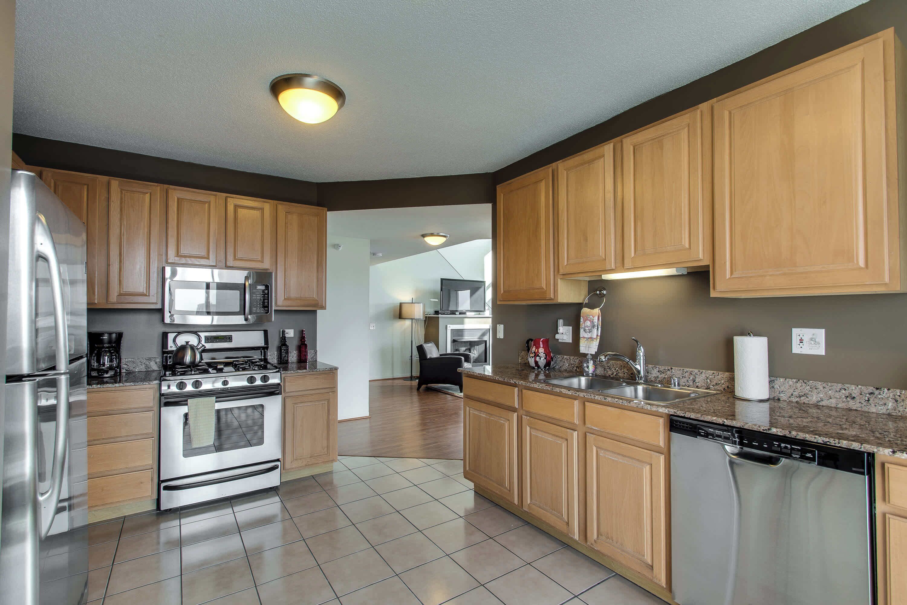 A modern kitchen with stainless steel appliances, wooden cabinets, and a granite countertop.