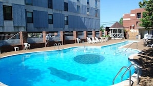 Una piscina amb una zona de banyera d'hidromassatge circular, envoltada de gandules i un porxo.