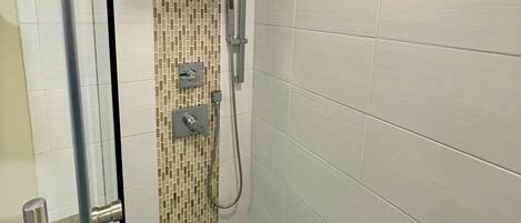 A modern shower with a square showerhead, a handheld showerhead, and a control panel.