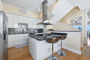 Una cocina moderna con armarios blancos, encimera negra y campana extractora de acero inoxidable.