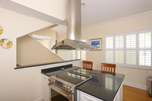 Una cocina con extractor de acero inoxidable, horno empotrado y encimera negra.