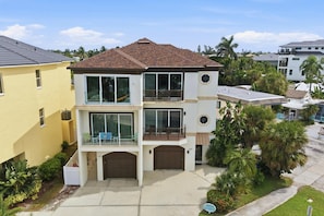 A two-story residential building with a balcony on the upper floor, a garage, and a well-maintained lawn.