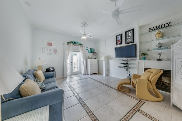 A spacious living room with a blue sofa, a tan armchair, a flat-screen TV, and a fireplace.