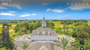 Un grand bâtiment historique doté d’une tour centrale, entouré d’une végétation luxuriante et d’un parcours de golf.