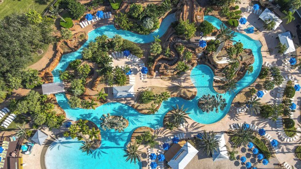 Vue aérienne d’un complexe hôtelier doté de plusieurs piscines, d’espaces de détente et de palmiers.
