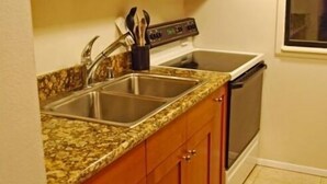 Una cocina con armarios de madera, encimera de granito, microondas, estufa y lavavajillas.