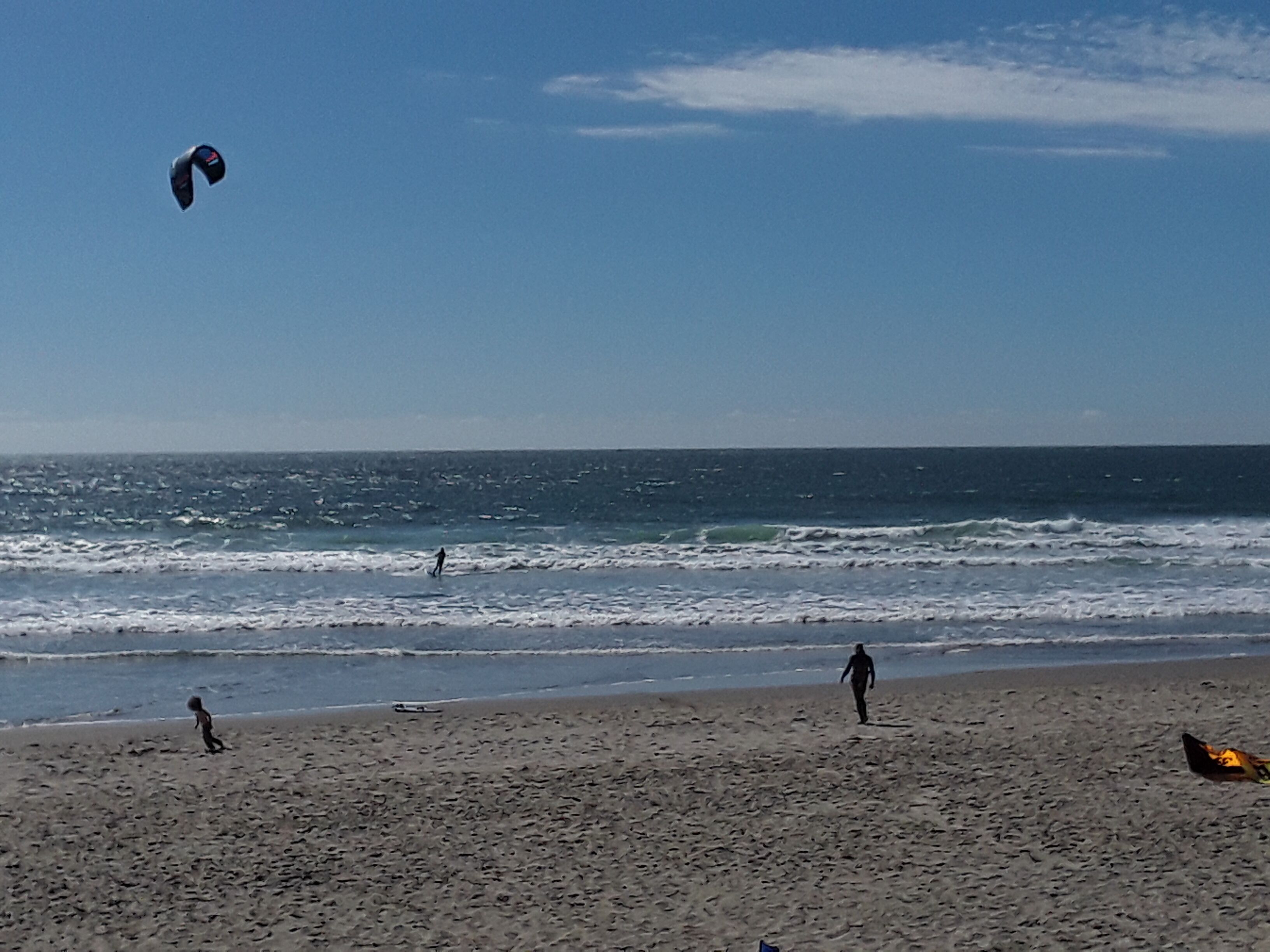 Ein Strand mit Menschen und einem Drachen.