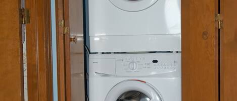 A front-loading washing machine in a laundry room with wooden doors.