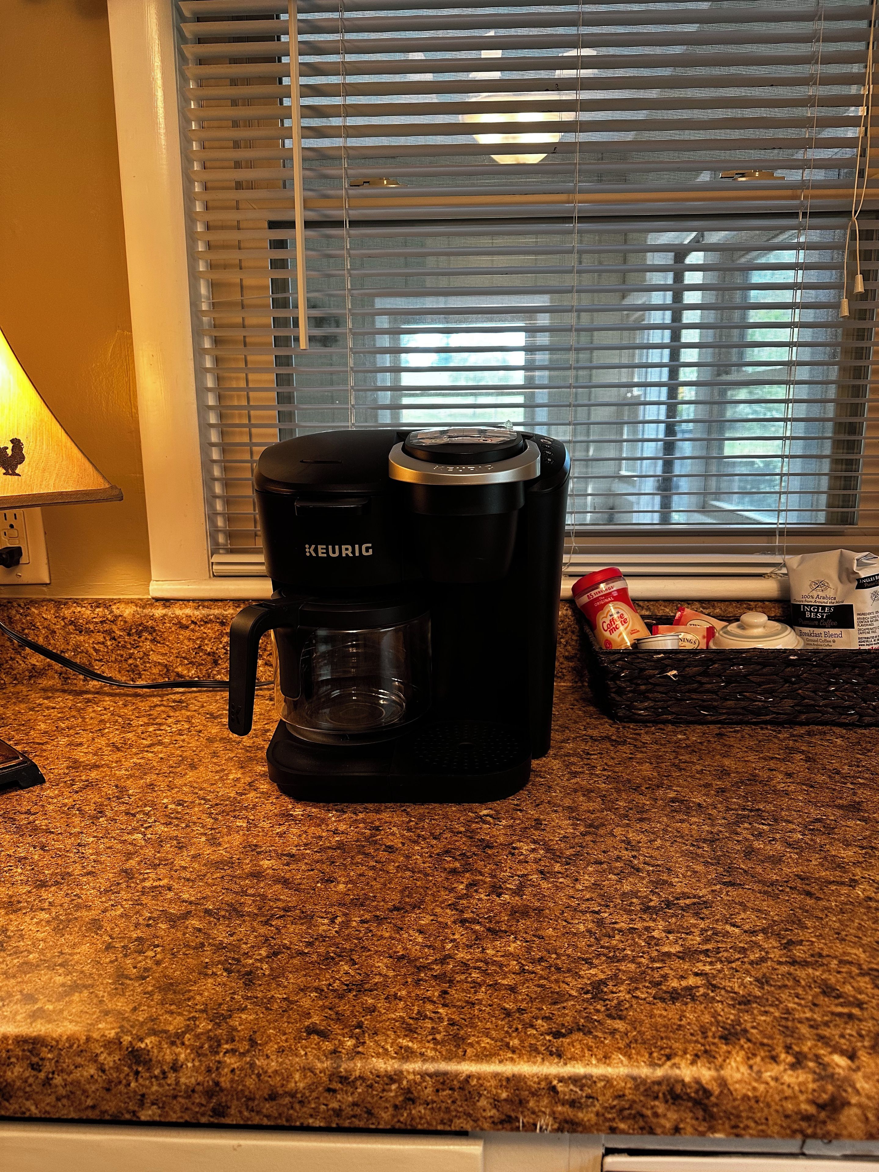 Una cafetera Keurig sobre una encimera de cocina con una ventana al fondo.