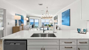 Cozinha moderna com uma ilha grande, eletrodomésticos de aço inoxidável e vista para o exterior.
