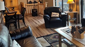 Una sala de estar acogedora con un sofá de cuero, una mesa de comedor de madera y una chimenea.