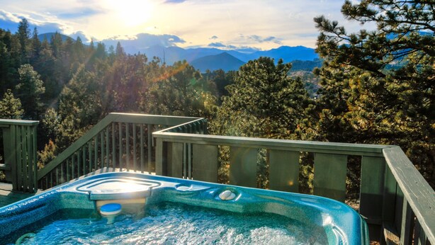 Un jacuzzi con terraza de madera y vista panorámica a las montañas.