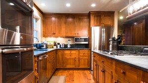 A kitchen with wooden cabinets, stainless steel appliances, and a black countertop. - Stunning Family/Friends Retreat,110 Private Acres, Renovated Historic Home (Madison)