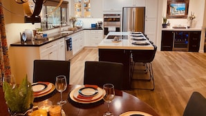 A modern kitchen with white cabinets, a central island, and a dining area set for six.