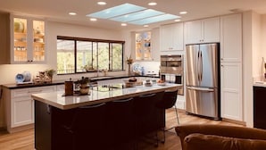 A modern kitchen with a central island, built-in cabinets, and a large window providing natural light.