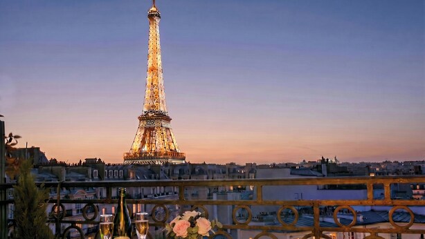A table with a bottle, glasses, and flowers, overlooking the Eiffel Tower at dusk. - Stunning & Bright, Sleeps 6, w/Big Balcony and Amazing Paris Views (Paris)