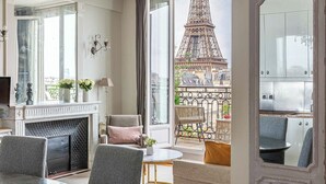 A modern living room with a fireplace, seating, and a view of the Eiffel Tower. - Stunning & Bright, Sleeps 6, w/Big Balcony and Amazing Paris Views (Paris)