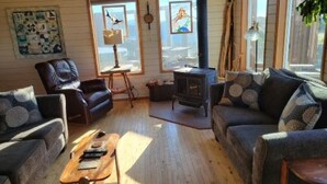 Ein gemütliches Wohnzimmer mit Kamin, Holzböden und großen Fenstern.