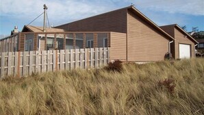 Einbungalow mit geneigtem Dach, Holzzaun und Garage.