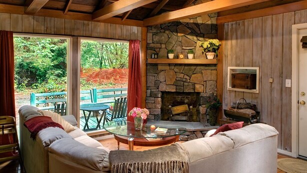 Una sala de estar acogedora con chimenea de piedra, vigas de madera y una mesa de centro de cristal.