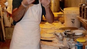 Una persona en una cocina con un horno industrial grande, varios utensilios de cocina e ingredientes sobre la encimera.