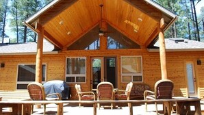 A wooden cabin with a covered porch, wicker chairs, and a table.