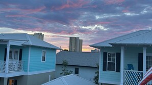 Un quartier résidentiel avec des maisons, une voiture et un ciel dégagé avec quelques nuages.