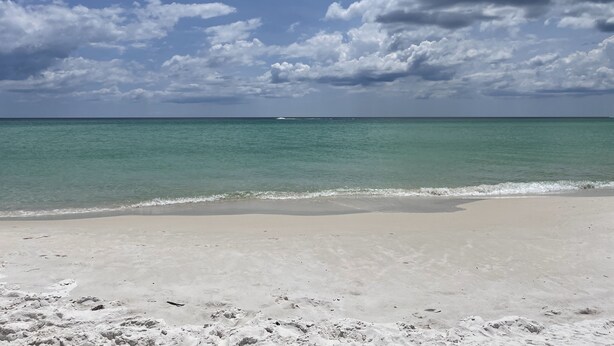 Une plage à l’eau turquoise et limpide, bordée d’un rivage sablonneux.