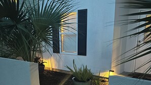Une maison moderne à l’extérieur blanc, dotée d’une terrasse en bois et agrémentée d’une plante en pot au premier plan.
