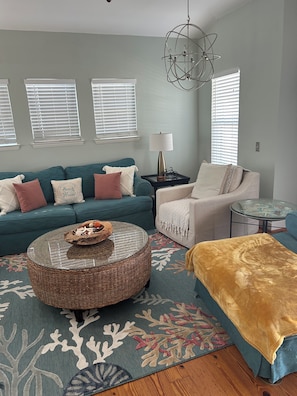 A living room with a teal sofa, a round coffee table, a beige armchair, and a patterned rug.