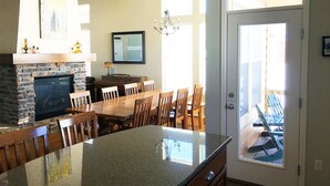 A kitchen with a granite countertop, wooden chairs, a dining table, a fireplace, and a door leading to a patio area.