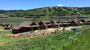 A resort with multiple cabins, a ski slope in the background, and a clear sky.
