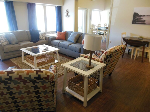 A living room with a sofa, two armchairs, a coffee table, and a dining area with a table and chairs.