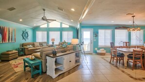 A spacious living room with a large sofa, a dining table, and a ceiling fan. - 7 Bedroom Beach House with POOL!! Gulf Front and Bay Front (Alligator Point)