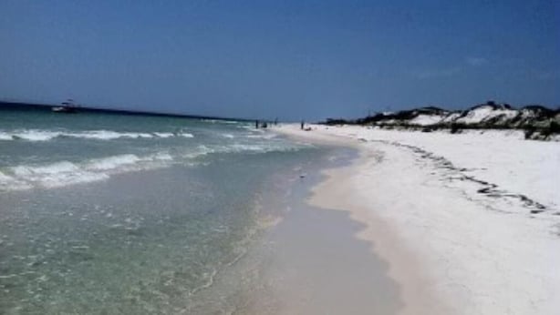 A beach with clear water, white sand, and a boat in the distance. - 7 Bedroom Beach House with POOL!! Gulf Front and Bay Front (Alligator Point)